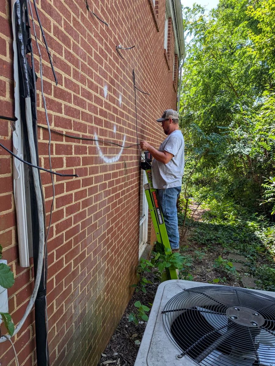CMV technician mounting a network interface device at a customer premise