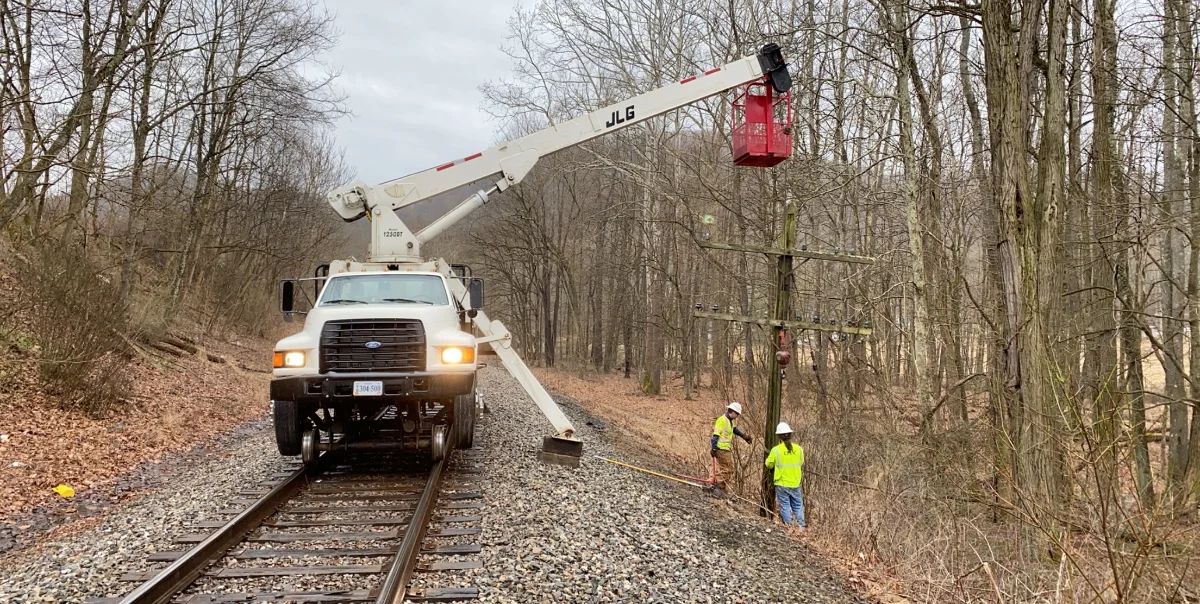 CMV hi-rail bucket truck working a pole line along an active rail corridor